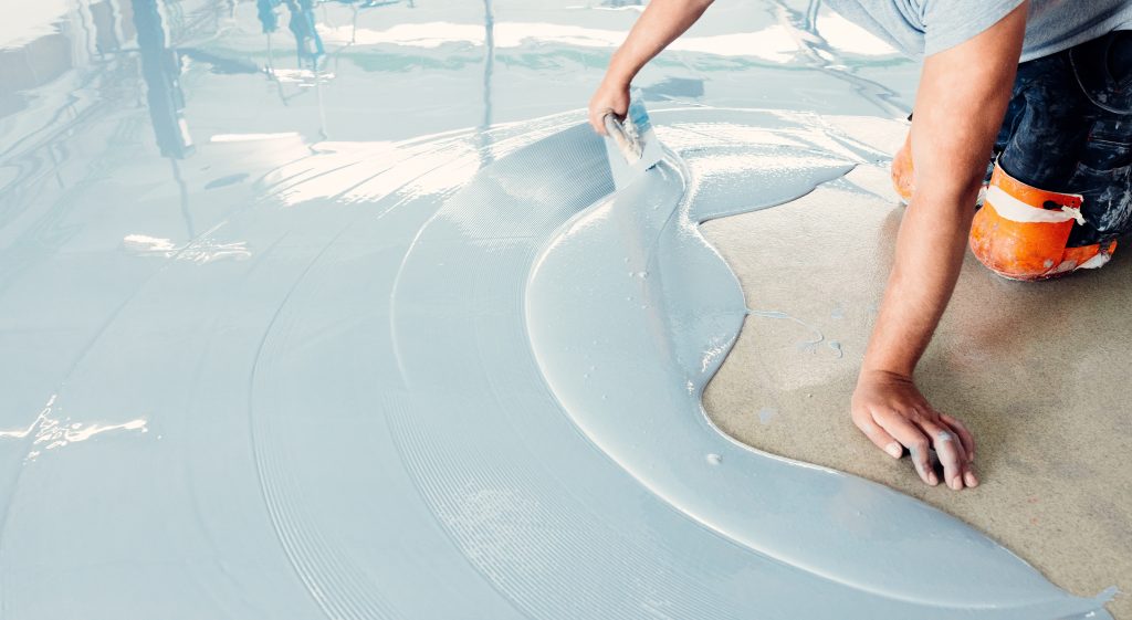 construction,worker,spreading,self leveling,concrete,mixture,over,the,floor,using